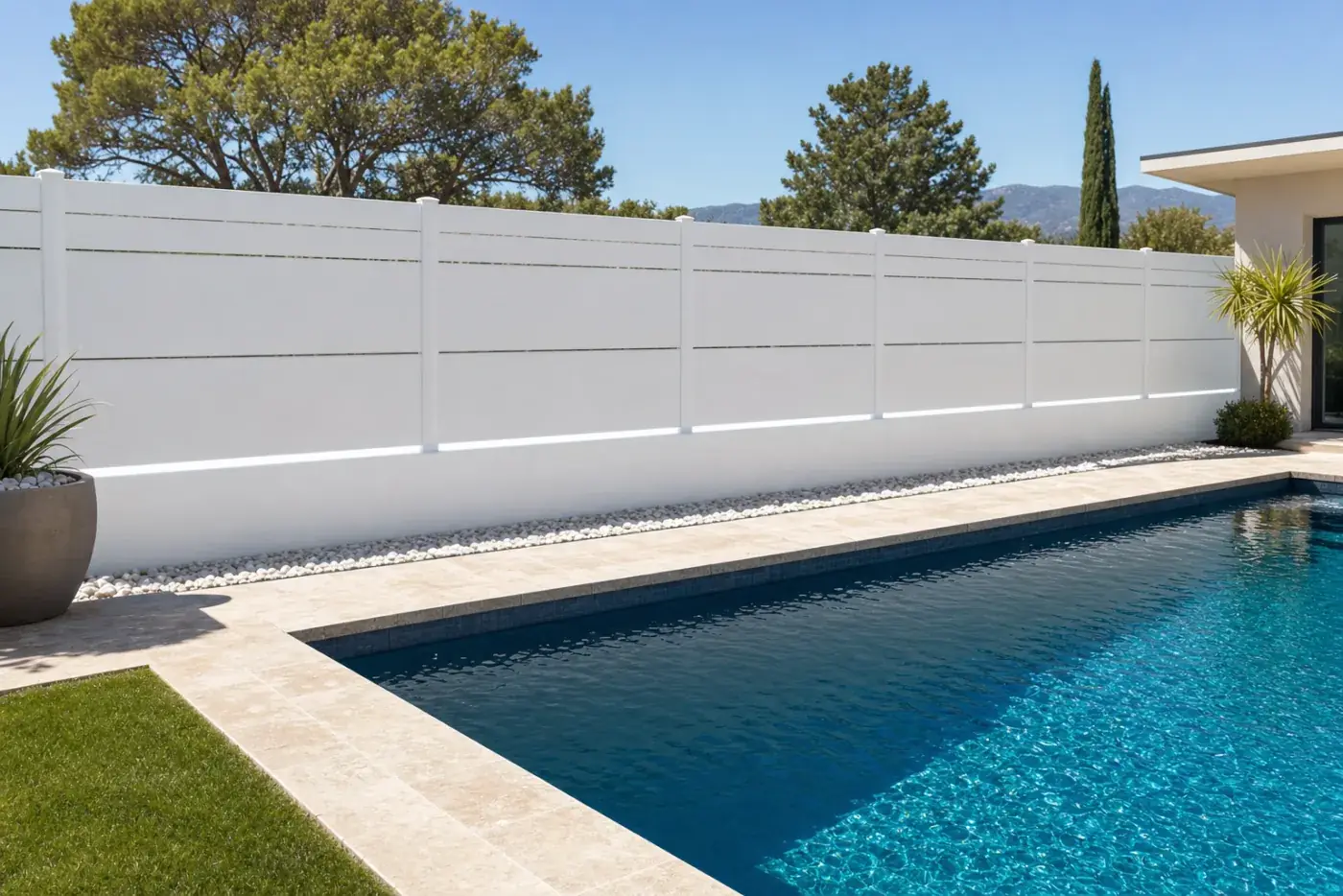 Tanca opaca íntima blanca al voltant d'una piscina amb gespa i cipresos