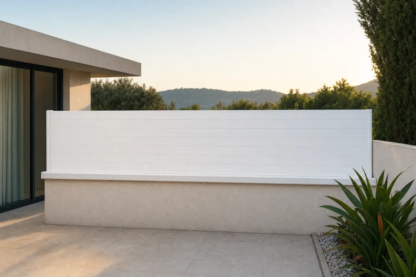 Tanca de lamel·la opaca blanca en un jardí residencial amb parterres de flors