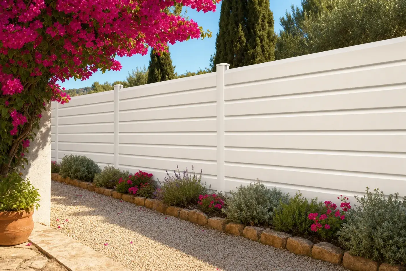 Tanca de lamel·la ventilada blanca en un jardí mediterrani amb buguenvíl·lea
